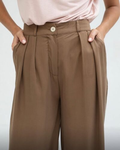 Pantalones de mujer en color marrón con pinzas y botón en la parte frontal, combinados con una blusa rosa, ideales para un look casual y elegante.