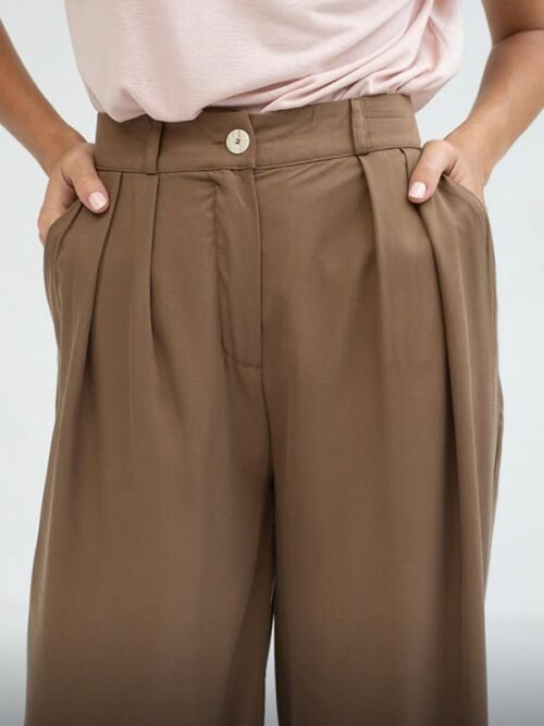 Pantalones de mujer en color marrón con pinzas y botón en la parte frontal, combinados con una blusa rosa, ideales para un look casual y elegante.