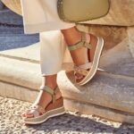 Sandalias de cuña en tonos nude y verde, con detalles de tachuelas, combinadas con un bolso de mano verde, perfectas para un look de primavera o verano.